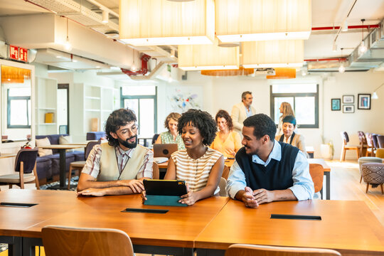 Diverse colleagues collaborating on tablet in modern coworking office