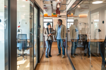 Business colleagues walking and discussing work in modern office