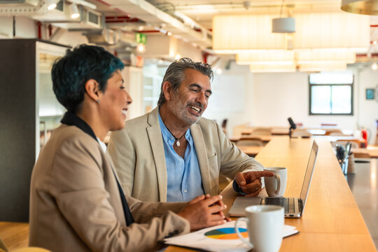 Diverse business colleagues collaborating on laptop in modern office