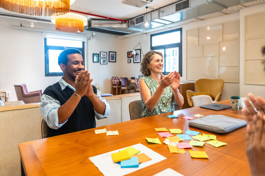 Diverse colleagues applauding successful brainstorming session in coworking office