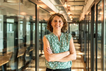 Professional woman standing confidently in modern office corridor