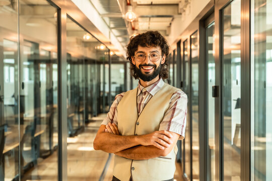Business professional smiling with crossed arms in modern office