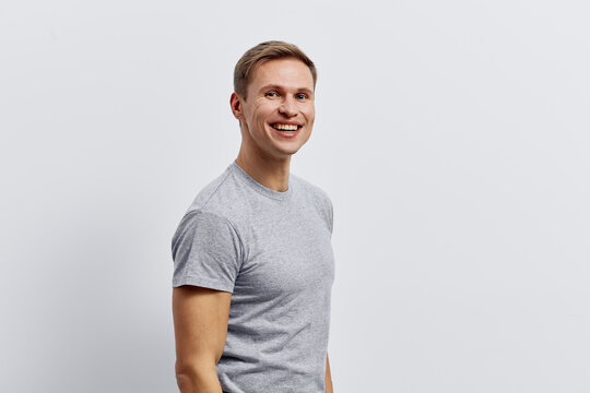 Smiling happy young caucasian man in grey t-shirt look camera standing isolated on plain light background technology concept digital nomad lifestyle remote work in metaverse