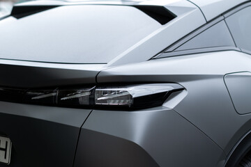 Modern car rear section closeup with sleek LED taillight design and matte gray finish.
