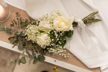 Elegant white roses arranged with baby’s breath and eucalyptus on a wooden table during a wedding setting in early evening light