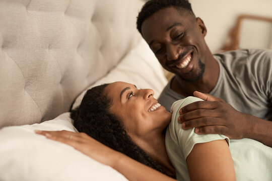 Smiling young multiracial couple waking up in bed in the morning - Powered by Adobe