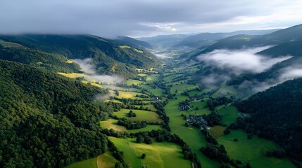 Naklejka premium Stunning aerial view of green valleys and hills in a misty landscape during early morning