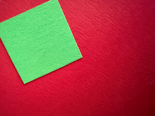 Felt composition in a festive Christmas palette. Green square for writing messages or text on a soft red surface. Abstract background with minimalist geometric design. Winter sale poster background