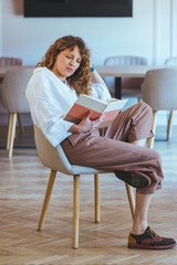 Woman Reading Book In Cozy Lounge Setting With Relaxed Mood And Casual Attire