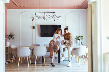Friendly Friends Review Tablet Together in a Bright Modern Dining Room During a Casual Business Meeting