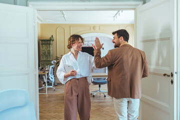 Casual Office High Five Between Colleagues Celebrating Success in a Bright Modern Workspace
