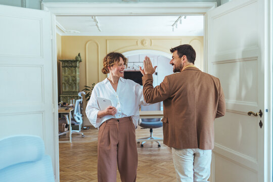 Casual Office High Five Between Colleagues Celebrating Success in a Bright Modern Workspace