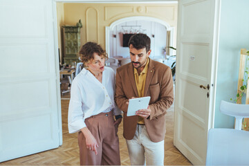 Professional Couple Reviewing Tablet During Collaborative Business Discussion in Bright Modern Home Office