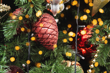 Christmas tree with red ball as pine cone and lights garland. Xmas card. Close up. Winter. Outdoors.