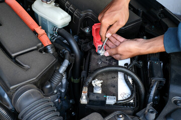 A mechanic replacing a car battery, tightening the terminal connection inside the engine bay. Perfect for vehicle maintenance, repair tutorials, automotive service, and battery replacement guides