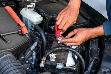 A mechanic replacing a car battery, tightening the terminal connection inside the engine bay. Perfect for vehicle maintenance, repair tutorials, automotive service, and battery replacement guides