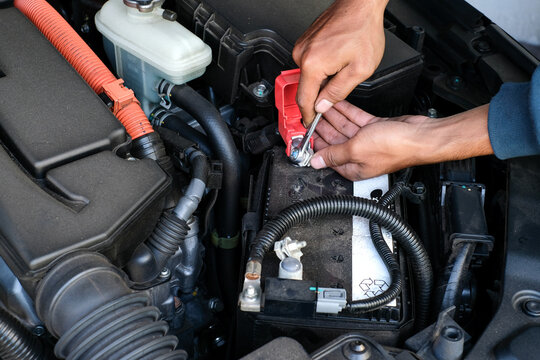A mechanic replacing a car battery, tightening the terminal connection inside the engine bay. Perfect for vehicle maintenance, repair tutorials, automotive service, and battery replacement guides - Powered by Adobe