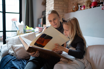 Mother and daughter reading photo album