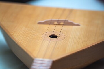Sound hole resonator beneath three strings on a traditional wooden balalaika