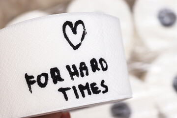 Handwritten text on a roll of toilet paper reads for hard times, emphasizing the importance of comfort during difficult moments. White background adds clarity.