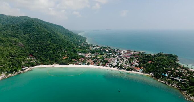 Tropical hills with a coastline meeting clear turquoise sea on a bright sunny day. Haad Rin. Ko Pha Ngan, Thailand.