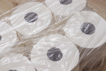 Close-up of multiple rolls of toilet paper wrapped in plastic, showcased on a wooden surface. Ideal for home supplies, hygiene concepts, and everyday necessities.