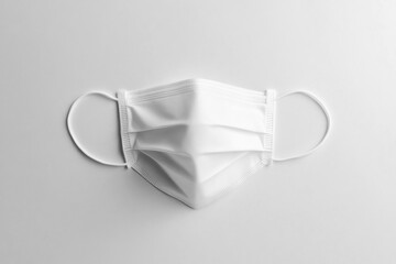Face mask with elastic loops resting on a white surface for health and safety measures
