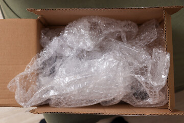 A cardboard box filled with crumpled bubble wrap, indicating packaging for fragile items. Ideal for e-commerce or shipping contexts, emphasizing protection and care.
