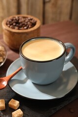 Aromatic coffee in cup, beans and brown sugar on table, closeup