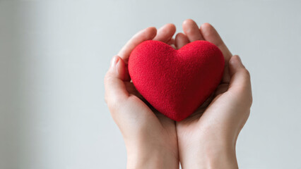 Two hands gently hold a vibrant red, fuzzy heart, symbolizing love, compassion, health, and giving. A gesture of care.