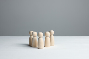 Many human figures on white wooden table against grey background. Space for text
