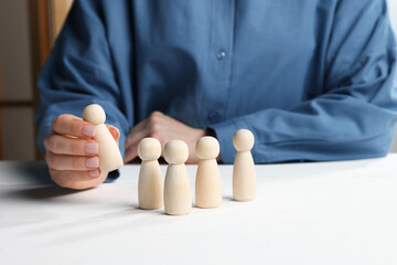 Woman with human figures at white wooden table, closeup