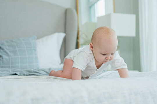 Happy baby. Cute little newborn girl with smiling face crawling on bed in bedroom. Infant baby resting playing lying down on blanket at home. Motherhood happy child childcare concept - Powered by Adobe