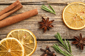 Different spices, dry orange slices and fresh rosemary for mulled wine on wooden table, flat lay