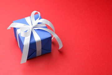 Beautiful gift box on red background, closeup. Space for text