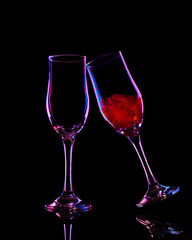 4K two wine glasses on black reflective surface with red and blue studio lighting, one glass tilted with wine, minimal commercial shot for advertising or design