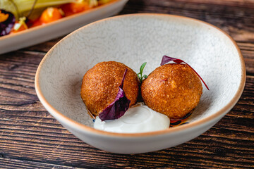Close-up of two fried croquettes served with creamy dip