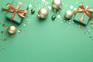Beautiful Christmas composition with gifts and decor on green background, flat lay. Space for text