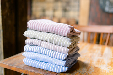 Beautiful stack of folded striped linens on wooden table, perfect for creating a cozy and inviting atmosphere in your home or showcasing quality textiles for sale