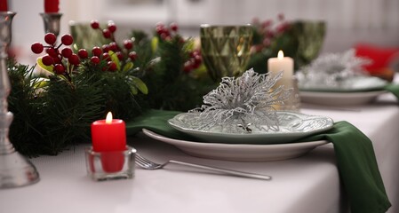 Festive table setting with Christmas decor and burning candles indoors, closeup