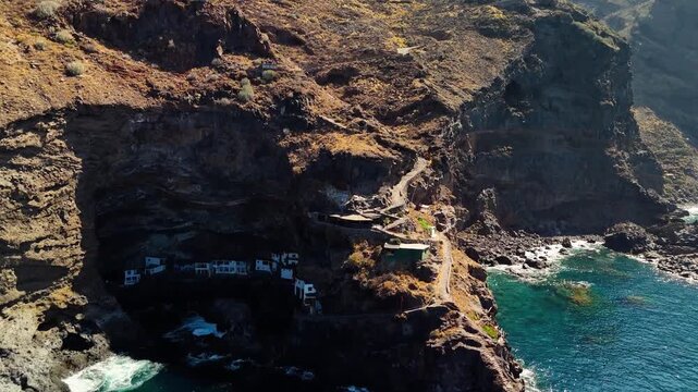 Aerial drone flight over the Atlantic Ocean towards the hidden Por&iacute;s de Candelaria fishing village, nestled in a massive sea cave cliff on La Palma, Spain.