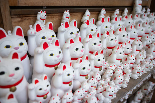 Many maneki neko beckoning cat statues in a row at Gotokuji Temple in Japan