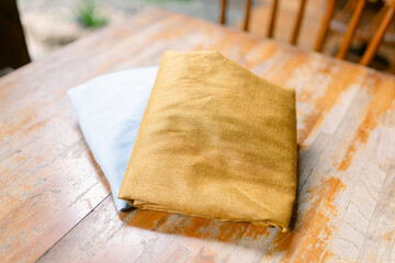 Stunning gold and light blue fabric layers create a unique texture on a rustic wooden table top, perfect for design mockups or textile showcasing, ideal for interiors