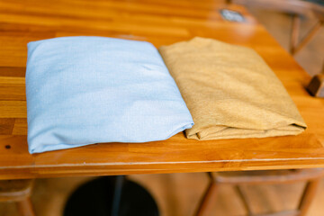 Invite relaxation with these stylish blue and tan cushions resting on a polished wooden table, adding warmth and a touch of modern elegance to your living space or cafe decor