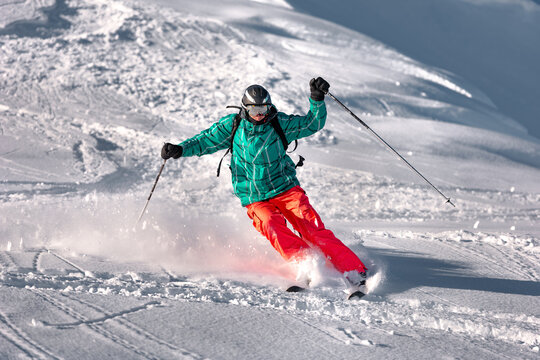 View of skier skiing downhill during sunny day in high mountains. Winter sports and leisure activities