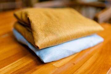 Stylish soft blue and mustard yellow linen bedding folded on a warm wooden surface creates a cozy and inviting ambiance for your home design projects