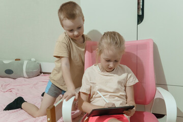 Girl and boy using digital tablet with stylus pen. Kids learning and playing with modern technology. Caucasian siblings enjoying educational game.