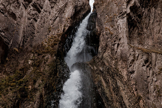 Waterfall cascades down rocky cliffs in Kabardino-Balkaria. The surrounding landscape features rugged terrain and natural rock formations.