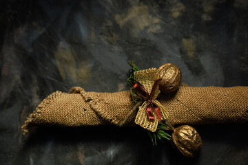 Golden ornaments and burlap ribbon on a dark surface with strong contrast in a brown-gold palette.Concept of atmospheric holiday styling, banner design and winter editorial visuals.