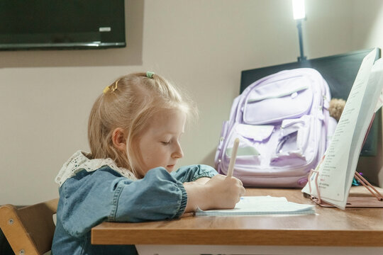Man cutting a birthday cake for a little girl and boy in party hats next to a happy birthday chalkboard. Family celebration with sweets.